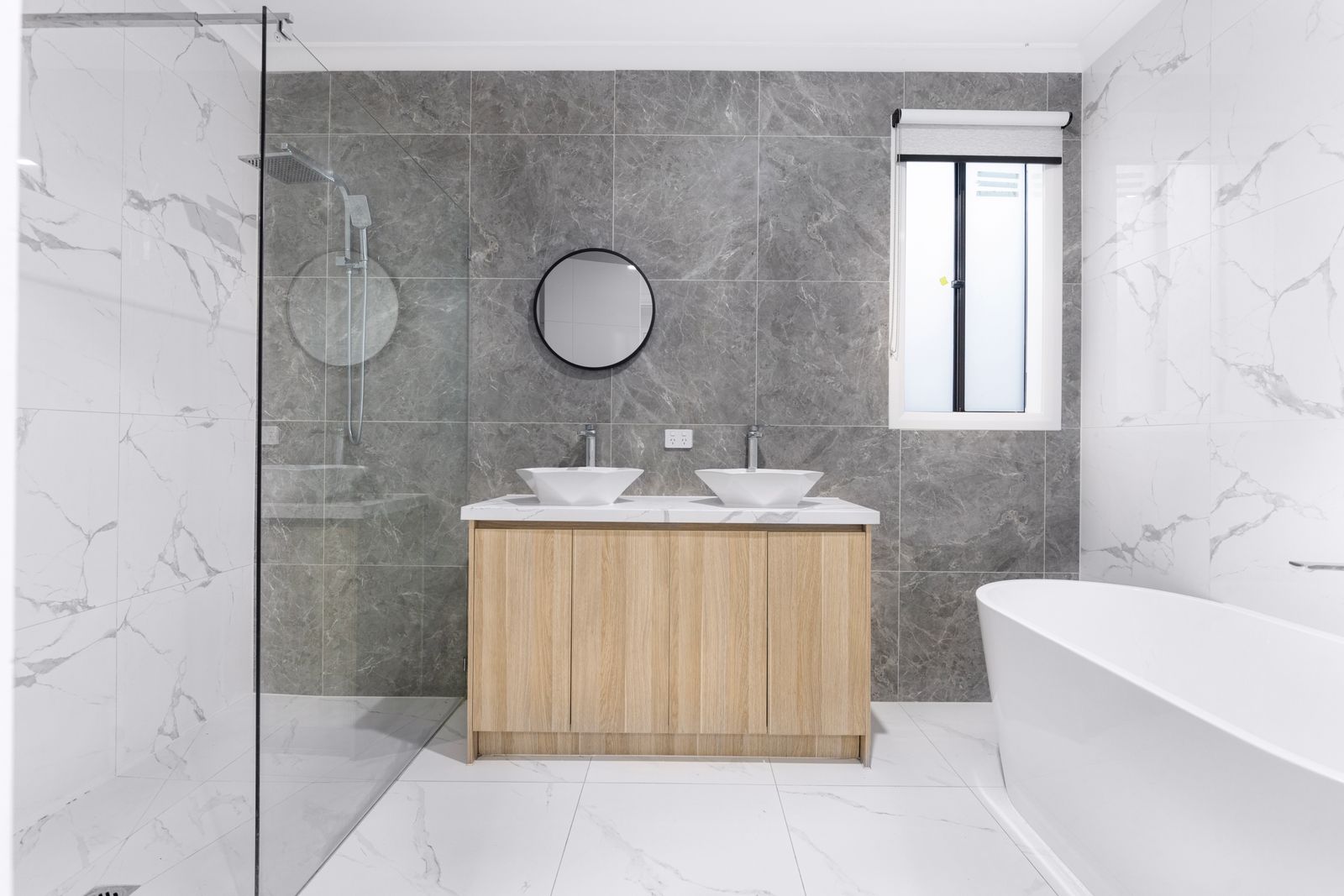 A sleek and stylish modern bathroom with minimalist design, featuring dual washbasins, marble tiles, and a glass shower enclosure.
