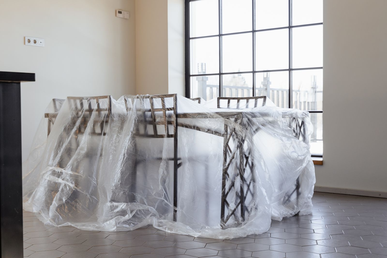 Dining chairs and table covered in plastic, a new home interior ready for moving in.